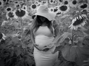 pregnant woman in hat posing in sunflowers field